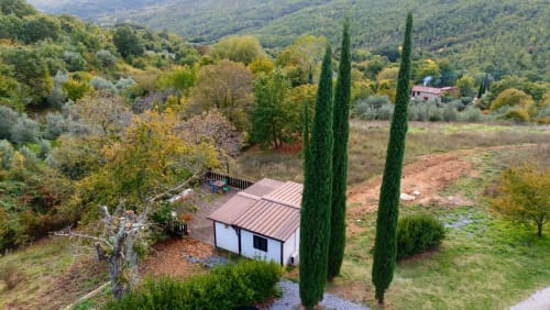 Casetta in legno con terrazza immersa nel verde di Santa Fiora, circondata da cipressi e vista sulla valle toscana
