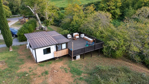 Villa in legno moderno con terrazza a Podere di Maggio, Santa Fiora. Casolare privato circondato da alberi e colline verdi.