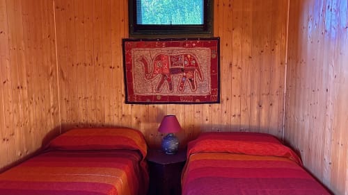 Due letti rossi nella camera in villa in legno a Podere di Maggio, Santa Fiora, con arazzo di elefante e vista sulle montagne