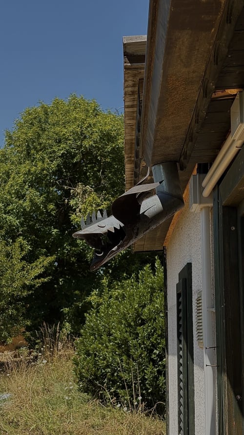 Scultura di drago nero su edificio in mattoni a Podere di Maggio, Santa Fiora, con vista del giardino verde