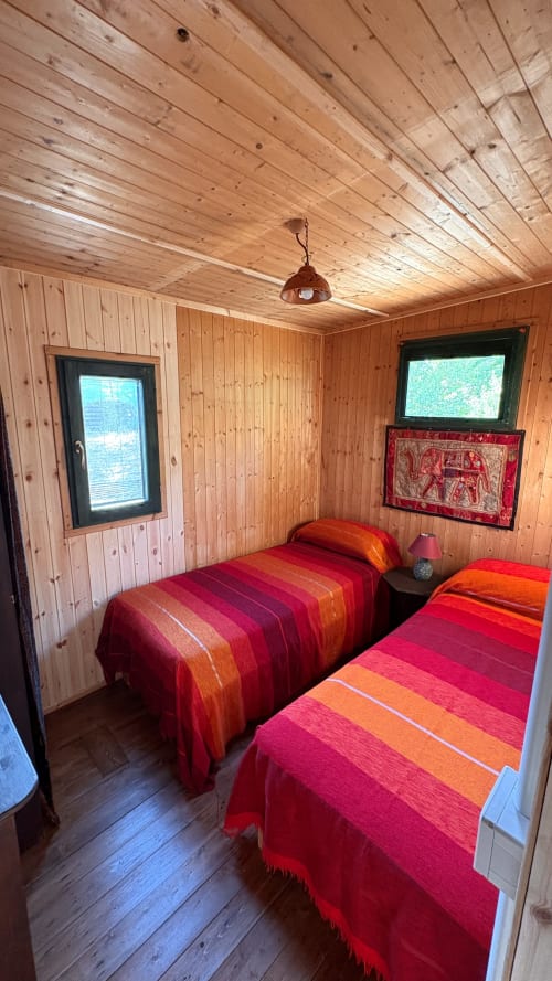 Camera da letto in legno con due letti a righe rosse, finestre e soffitto in legno di pino rustico a Podere di Maggio a Santa Fiora