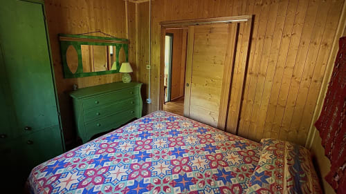 Accogliente camera da letto in legno a Podere di Maggio a Santa Fiora con biancheria colorata, cassettone verde e legno di pino