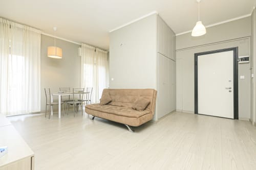 Soggiorno moderno a Genova con divano beige, zona pranzo e vista sulla città presso ML White House