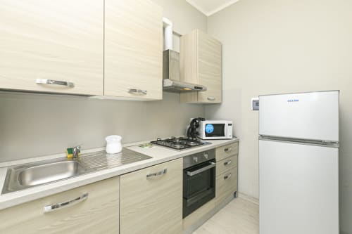 Cucina moderna nell'appartamento di Genova con mobili bianchi, fornello a gas, microonde e frigorifero Ocean