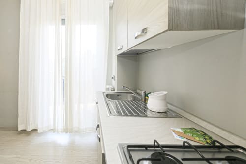 Cucina moderna nell'appartamento EDERA HOUSE a Genova, con mobili bianchi, piano cottura a gas, scolapiatti e luce naturale abbondante