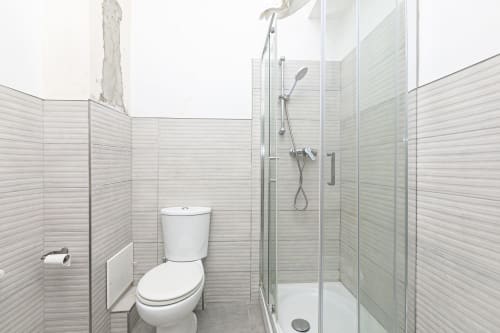 Bagno moderno nell'appartamento di Genova con wc bianco, cabina doccia in vetro e piastrelle grigio chiaro