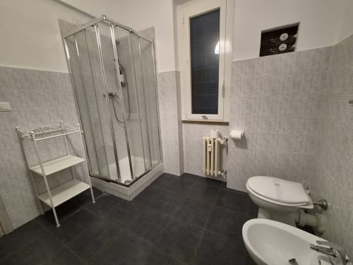 Bagno moderno nell'appartamento Vanilla House a Genova. Dotato di box doccia, toilette, bidet, radiatore e piastrelle bianche.