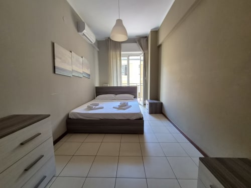 Camera da letto Vanilla House nell'appartamento di Genova con letto matrimoniale, lampada a sospensione, balcone e pavimenti in piastrelle