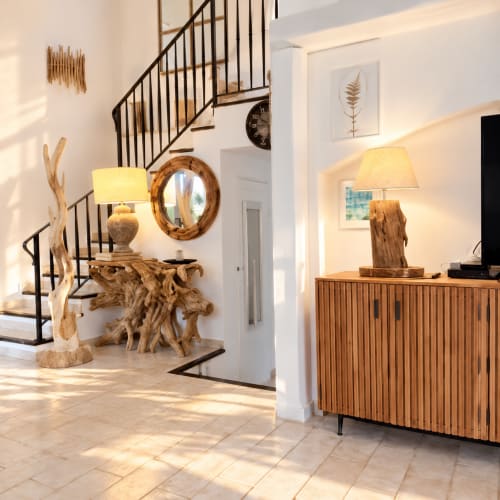 Entrée de villa moderne aux Villas d'A Storia avec escalier hélicoïdal, console en bois flotté et ambiance chaleureuse à Lecci
