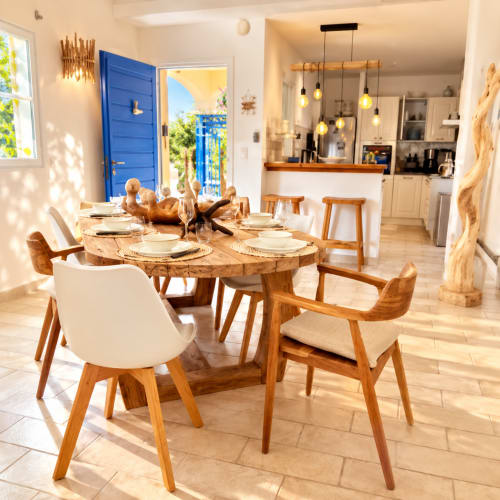 Salle à manger lumineuse avec table en bois, chaises blanches et luminaires suspendus modernes à la villa Les Villas d'A Storia à Lecci