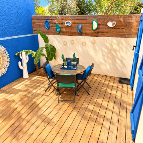Patio coloré de villa aux Villas d'A Storia avec murs bleus, terrasse en bois, table à manger et décoration inspirée de l'océan à Lecci