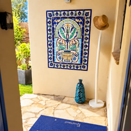 Fresque murale en carrelage bleu et blanc à motif floral ornant l'entrée de la villa aux Villas d'A Storia