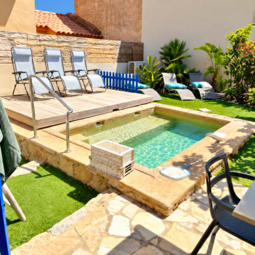 Ambiance ensoleillée à la piscine des Villas d'A Storia à Lecci - chaises longues, piscine turquoise étincelante, jardin luxuriant