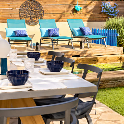 Espace de détente et restauration en plein air aux Villas d'A Storia avec chaises turquoise, tables dressées et vue sur la piscine à Lecci