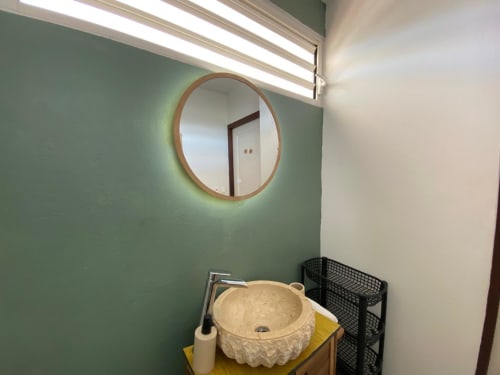 Lavabo moderne de l'appartement Hibis Gold aux Maisons En Or, Cayenne, avec miroir rond et murs verts
