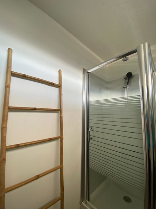 Salle de bain moderne avec échelle en bambou et douche vitrée à l'hôtel Maisons En Or de Cayenne, appartement Hibis Gold