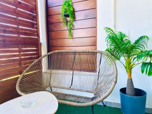 Fauteuil de salon tressé avec coussins vue jardin, appartement Hibis Gold à Maisons En Or, Cayenne