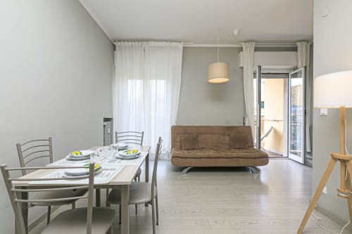 Moderno appartamento a Genova con tavolo da pranzo, divano futon marrone, illuminazione a sospensione e accesso al balcone in ERICA HOUSE