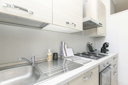 Cucina moderna nell'appartamento Erica House a Genova, con lavello in acciaio inox, piano cottura a gas e elettrodomestici compatti