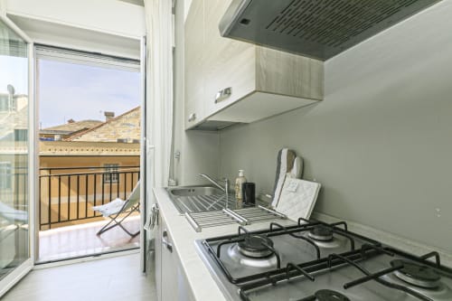 Cucina moderna nell'appartamento di Genova con fornello a gas, lavandino e vista balconata sui tetti della città
