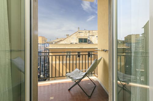 Balcone privato con vista sulla città presso l'appartamento ERICA HOUSE a Genova, con comodi sedili e facciata gialla dell'edificio