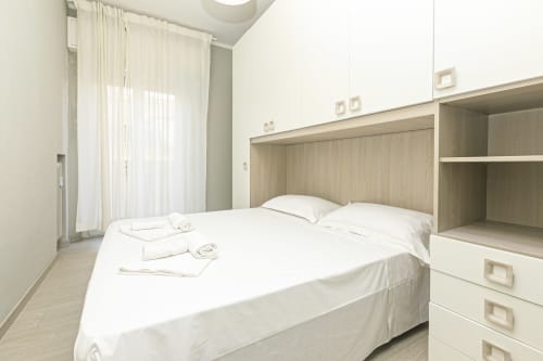 Camera luminosa con letto matrimoniale, biancheria bianca, testata in legno, ripiani aperti e vista città - ML White House, Genova