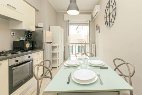 Cucina-soggiorno moderno nell'appartamento Papavero House a Genova, con tavolo da pranzo, cucina a gas e vista sul balcone