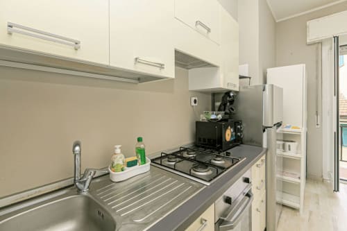 Cucina moderna con piano cottura a gas, lavello, mobiletti bianchi e elettrodomestici in acciaio inox nell'appartamento Papavero House, Genova