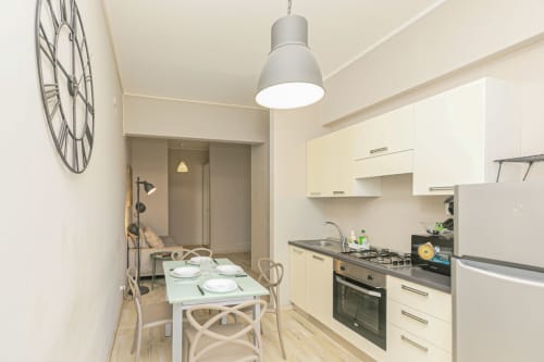 Cucina e zona pranzo moderne dell'appartamento Papavero House a Genova, con mobili bianchi, piano cottura a gas e tavolo per due persone