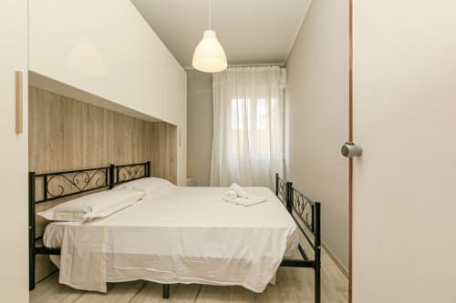 Camera luminosa di Papavero House, Genova con letto queen, testata nera ornamentale, lampada a sospensione e tende color crema
