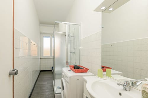 Bagno moderno nell'appartamento Papavero di ML White House a Genova con doccia, lavandino, lavatrice e pareti piastrellate bianche