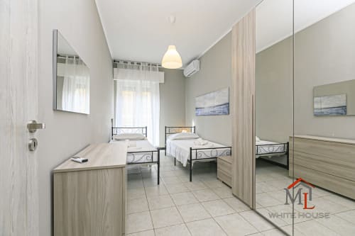 Camera da letto matrimoniale luminosa nell'appartamento ML White House a Genova, con armadio specchiato, due letti, lampada a sospensione e vista sulla città