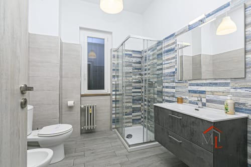 Bagno moderno di Ulivo House a Genova con doccia walk-in, vanity scuro, piastrelle righe e lampade a sospensione