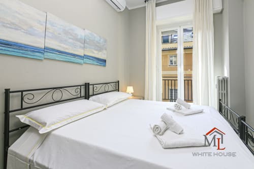 Luminosa camera da letto alla ML White House di Genova con letto matrimoniale, testata in ferro, opere d'arte con vista mare e panorami cittadini dal balcone