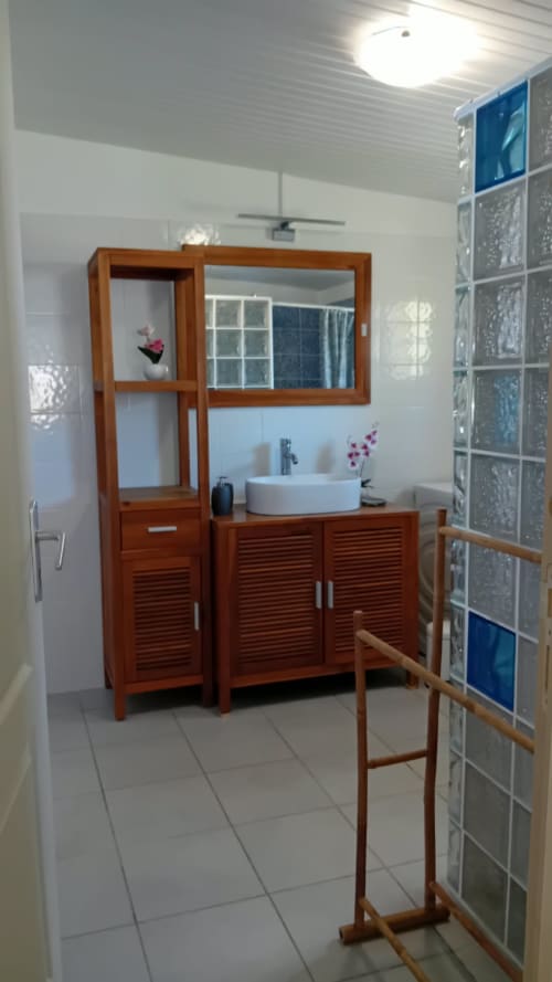 Vasque minimaliste blanche et miroir rond dans la salle de bain chic de la Villa Ti Soley Mafanga, Bouillante