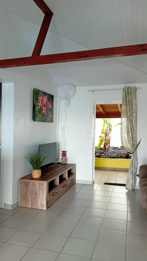 Villa lumineuse avec plafond à poutre rouge, meuble TV en bois, plante en pot et vue sur le jardin, Bouillante