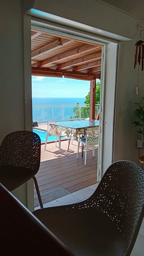 Villa Ti Soley Mafanga à Bouillante : terrasse avec vue mer, piscine, pergola en bois et horizon océanique depuis l'intérieur