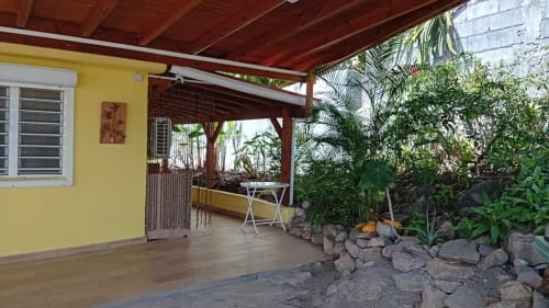 Terrasse couverte en bois de la Villa Ti Soley Mafanga à Bouillante, Guadeloupe, avec plantes tropicales, mobilier de jardin et vue sur mer
