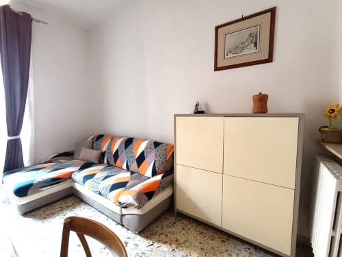 Camera da letto nell'appartamento Matilde Sweet Home a Roma, con biancheria a righe, guardaroba color crema e finestra con vista sulla città e dettagli viola
