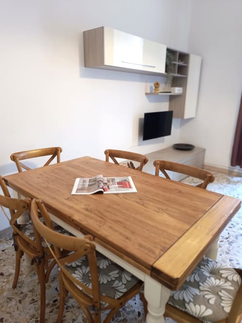 Tavolo da pranzo in legno con sedie nell'appartamento Matilde Sweet Home a Roma, con TV moderna a parete e ripiani dietro