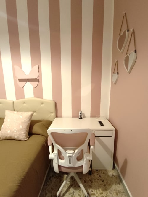 Camera da letto con righe rosa e bianche dell'appartamento Sweet Home Rome, con scrivania, sedia e decorazioni a forma di cuore