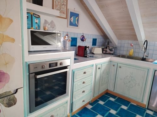 Cucina turchese luminosa nell'appartamento B&B di Oristano con alzatina in piastrelle blu, elettrodomestici bianchi e arredamento nautico