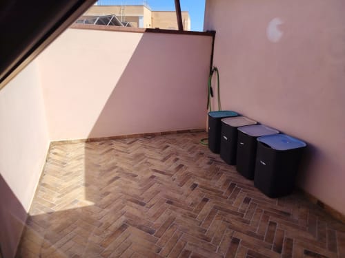 Appartamento rosa in terrazza con pavimento in legno a spina di pesce, bidoni della spazzatura e vista sulla città a Maison Belle Époque a Oristano