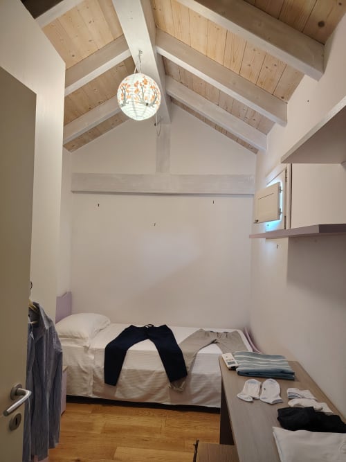 Luminosa camera mansardata presso Maison Belle Époque a Oristano con travi in legno a vista, plafoniera e vista sulla città