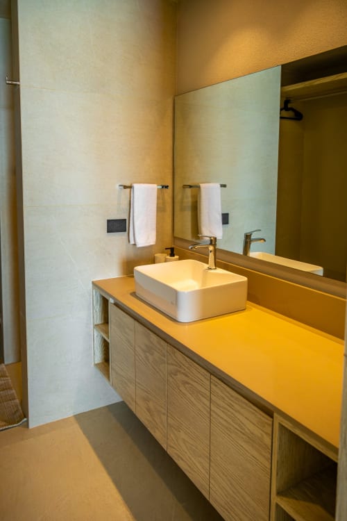 Baño moderno en Condominio Marlica con lavabo de cerámica blanca, mueble de madera y luminosidad cálida en Manzanillo