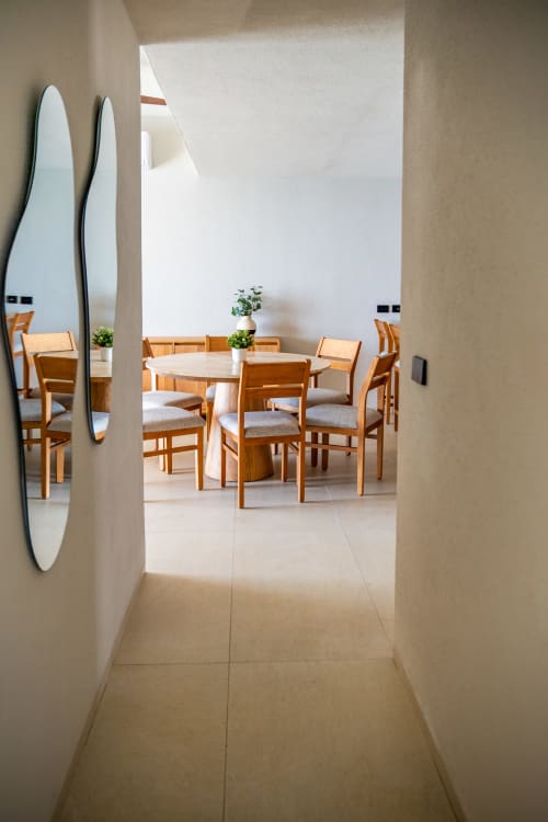 Comedor moderno en Condominio Marlica con mesa redonda, sillas de madera y tablas de surf frente al océano en Manzanillo