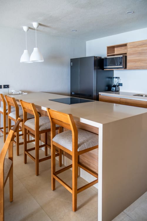 Moderna cocina y comedor en Condominio Marlica con bancos de madera y electrodomésticos negros en Manzanillo