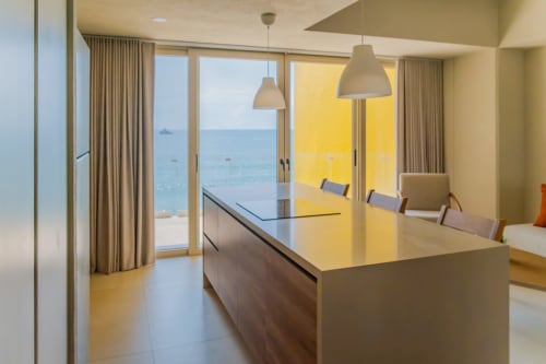 Cocina del Condominio Marlica con vistas al océano, isla moderna con luces colgantes y ventanales frente al mar en Manzanillo