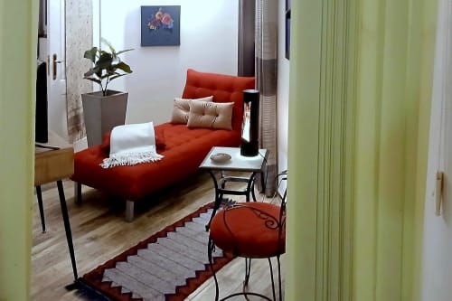 Sala de estar Casa Cisne com sofá vermelho, almofadas, mesa lateral, planta em vaso e obra de arte no hotel rural SELÃO DA EIRA no Alentejo
