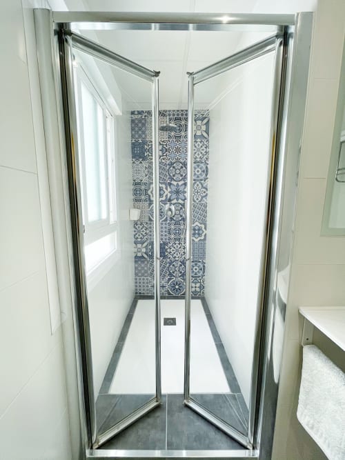 Douche moderne avec mur d'accent en carrelage bleu et blanc dans la salle de bain de la Pensión Alicante San Nicolás